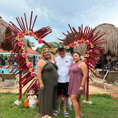 Tres viajeros de JAWAR posan frente a una decoración floral